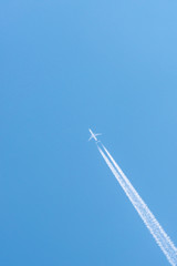 Airplane in a blue sky with clouds and condensation trails, Germany