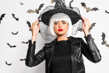 attractive woman in witch hat and wig looking at camera in Halloween