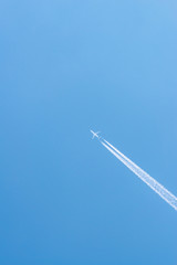 Airplane in a blue sky with clouds and condensation trails, Germany