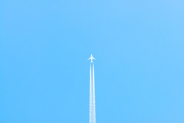 Airplane in a blue sky with clouds and condensation trails, Germany