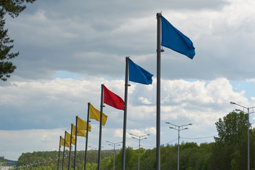 multicolored flags and lampposts on the background of clouds