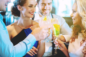 Men and women at the counter of a bar enjoying their drinks
