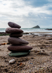 Pebbles in a stack with the Great Mew Stone island in the background