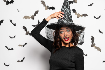 shocked woman in witch hat looking at camera in Halloween
