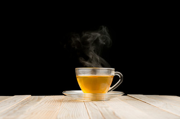 A cup of hot tea. In the tea there is a mixture of tea leaves. The concept of freshly brewed tea, black background