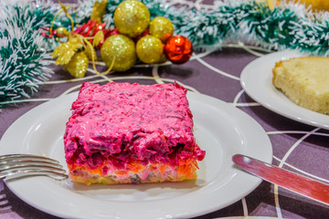 Dressed herring or herring under a fur coat. Symbol of the new year. Traditional Russian cuisine. Christmas decorations in the background. New Year's concept.