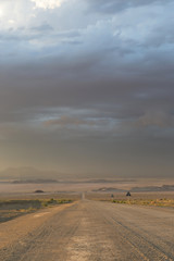 Fototapeta na wymiar Stormy skies above a gravel road through the desert