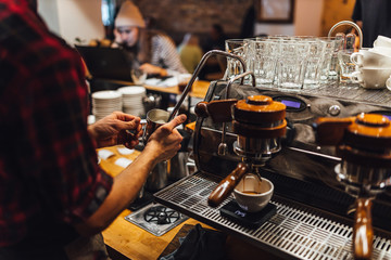 Barista making hot drink  in coffee shop, cappuccino brewing.