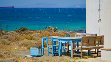 Old chairs and table in blue color on Aegean sea coast