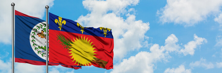 Belize and Guadeloupe flag waving in the wind against white cloudy blue sky together. Diplomacy concept, international relations.