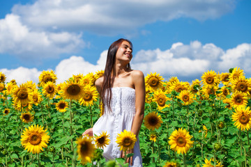 Naklejka na ściany i meble Portrait of a young beautiful girl in a field of sunflowers