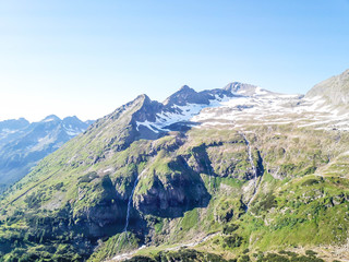 A panoramic view on Schladming Alps, partially still covered with snow. Spring slowly reaching the tallest parts of the mountains. Sharp peaks, slopes partially overgrown with lush green plants.