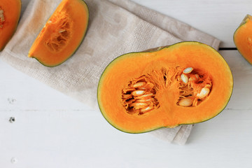 Group of halves and whole pumpkin on a light wooden background. Pumpkin is not cleared of seeds.