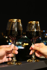 Glasses of Wine in Hands of a Happy Couple with the Night View in Backdrop