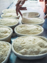 detail of the baker's hands putting bread dough in some bread baskets