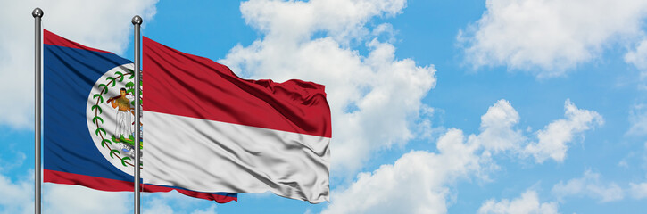 Belize and Indonesia flag waving in the wind against white cloudy blue sky together. Diplomacy concept, international relations.