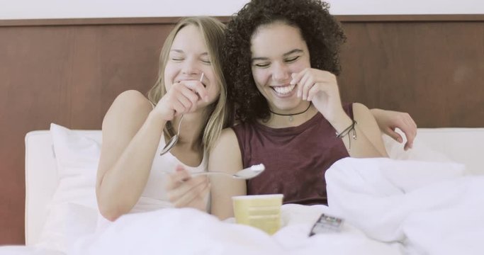 Girls eating ice cream in bed and having fun
