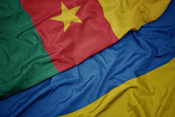 waving colorful flag of ukraine and national flag of cameroon.