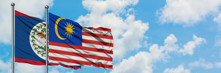 Belize and Malaysia flag waving in the wind against white cloudy blue sky together. Diplomacy concept, international relations.