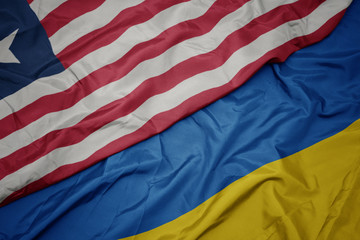 waving colorful flag of ukraine and national flag of liberia.