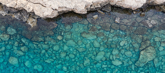 An aerial view of the beautiful Mediterranean sea, where you can se the rocky textured underwater corals and the clean turquoise water of blue lagoon Agia Napa