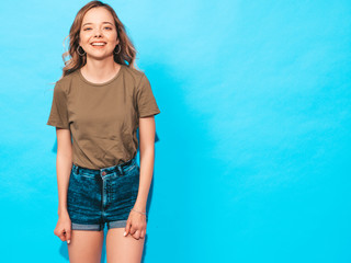 Fototapeta na wymiar Young beautiful woman looking at camera. Trendy girl in casual summer shirt clothes with natural makeup. Positive female smiling. Funny model posing near blue wall in studio
