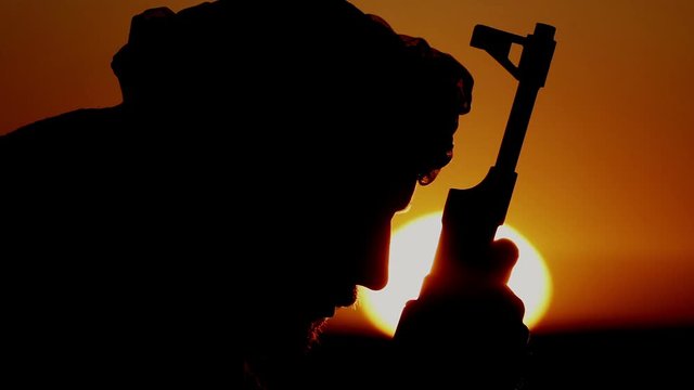 Portrait of a warrior bowing his head over a machine gun. militant prays to Allah over the machine gun.