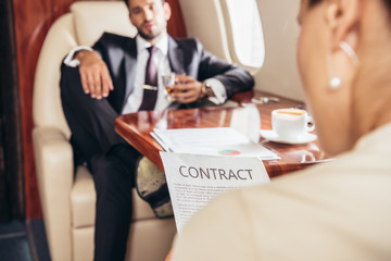 selective focus of businesswoman reading contract in private plane