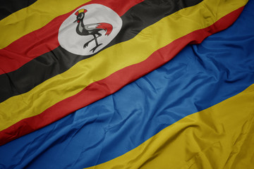 waving colorful flag of ukraine and national flag of uganda.