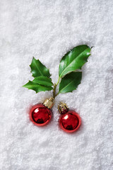 Christmas ornaments with holly berry in snow background viewed from above. Top view