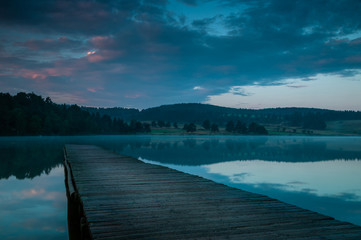 Naklejka premium wooden jetty on lake at sunrise.