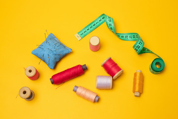 Accessories and tools for sewing on a yellow background. Top view, flat lay. Copy space for text.