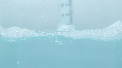 Water and bubbles with a syringe dip in blue water