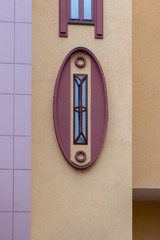 Obraz premium A beautiful oval window with an unusual design, the facade of a modern building. Rectangular metal grill on an oval window