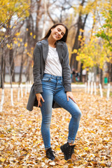 Portrait of a young beautiful girl in blue jeans and gray coat