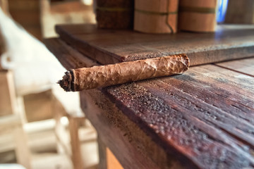 Hand made Cuban cigar rests on the edge of a table