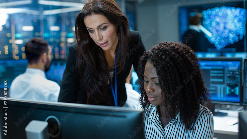 Poster Female Team Leader Consults Young Computer Engineer. They Work in a Crowded Office on a Neural Network/ Artificial Intelligence Project.