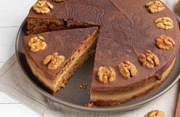 Closeup homemade Walnut Cake with Chocolate Icing on white wooden table