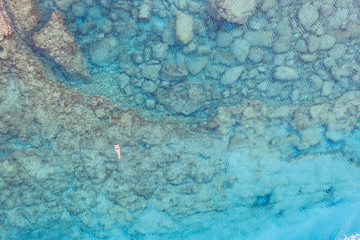 An aerial view of the beautiful Mediterranean sea, where you can se the rocky textured underwater corals and the clean turquoise water of blue lagoon Agia Napa