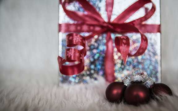 Imagen de Navidad, con bolas rojas y caja de regalo con lazo rojo y desenfoque