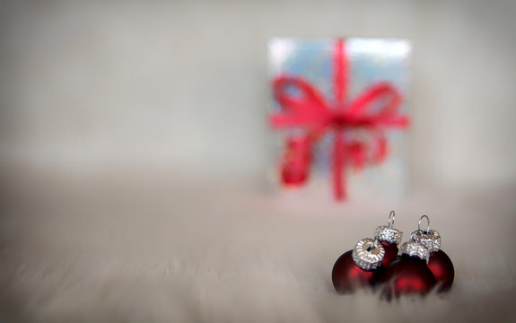Imagen de Navidad, con bolas de color rojo y en el fondo una caja de regalo con desenfoque