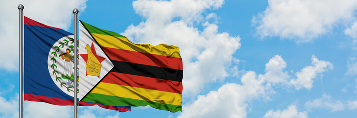 Belize and Zimbabwe flag waving in the wind against white cloudy blue sky together. Diplomacy concept, international relations.