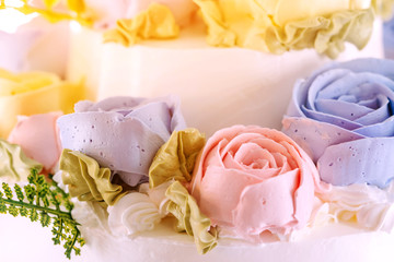 Close up to wedding cake decorated with roses and flowers for the groom and the bride in the wedding day.