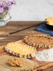 Cooking national dishes Karelian pies. In the foreground pies prepared for baking. A traditional dish of Karelia and Finland from rye flour with different fillings. Close-up