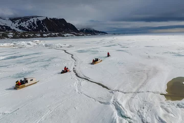 Fotobehang Aerial drone photo of tourists travelling by Qamutiik on the sea ice near Sirmilik National Park in Nunavut, Canada © Colin