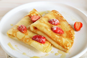 Homemade crepes with strawberry, honey and powdered sugar