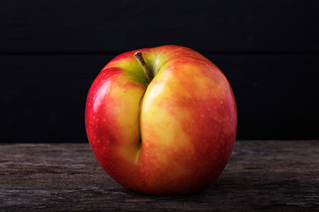 One red apple close up and copy space on the background of a rusty table. An ugly apple with rot.