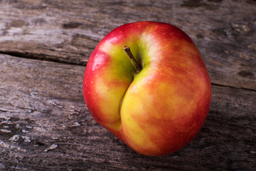 One red apple close up and copy space on the background of a rusty table. An ugly apple with rot.