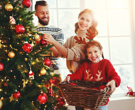 happy family mother, father and child daughter decorate Christmas tree  .