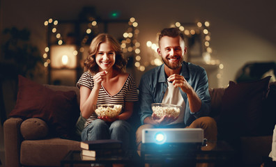 Family couple watching television projector at home on sofa.